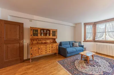 a living room with a blue couch and a wooden cabinet at Casa Tre Corone, sulla strada per Cortina in Borca di Cadore