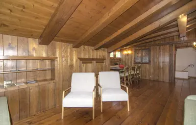 a living room with wooden walls and white chairs at Appartamento panoramico vicino centro in Cortina dʼAmpezzo