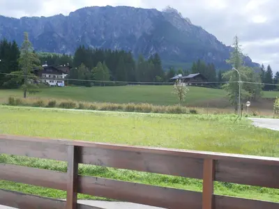 a wooden fence in front of a field with mountains at Ca dell'Alba in Cortina dʼAmpezzo