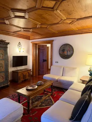 a living room with white furniture and a wooden ceiling at Ca dell'Alba in Cortina dʼAmpezzo