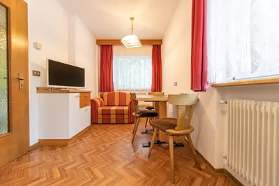 a room with a table and chairs and a television at Apartments Jasmin in Selva di Val Gardena