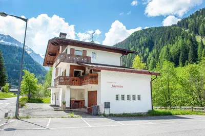 a building in a parking lot with mountains in the background at Apartments Jasmin in Selva di Val Gardena
