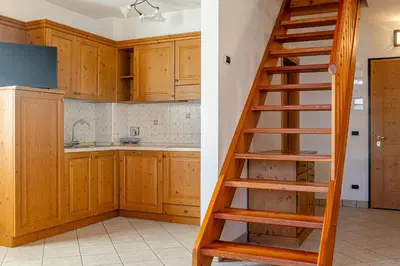 a kitchen with wooden cabinets and a table and a chair at Appartamenti Villa Elisa - Falcade in Falcade
