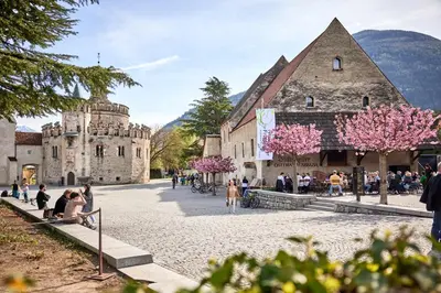 a group of people sitting on a sidewalk in front of a building at Praterhof Chalet in Südtirol - Natur, Ruhe & Bergblick in Bressanone