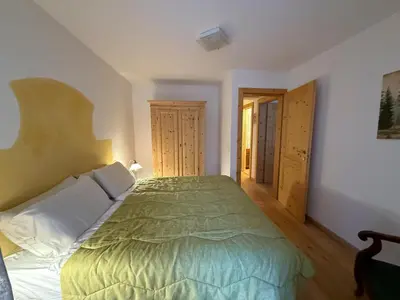 a bedroom with a bed with a green comforter at Il Molino nel bosco - PT in Alleghe