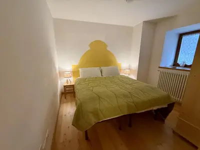 a bedroom with a bed with a green bedspread at Il Molino nel bosco - PT in Alleghe