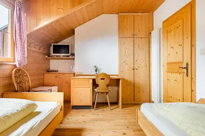 a bedroom with a bed and a desk in a room at Room Erika, Obertörgglerhof in Brixen