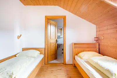 two beds in a small room with a hallway at Room Erika, Obertörgglerhof in Brixen