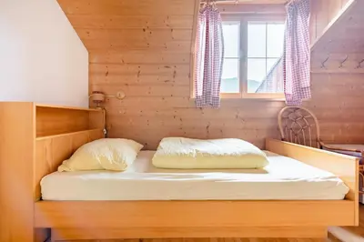 a bed in a wooden room with a window at Room Erika, Obertörgglerhof in Brixen