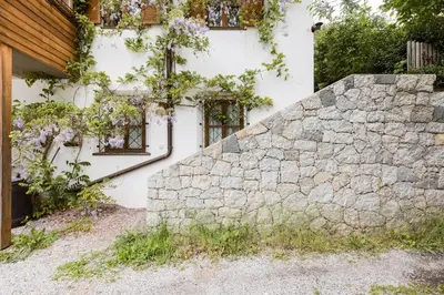 a stone retaining wall next to a house at Room Erika, Obertörgglerhof in Brixen