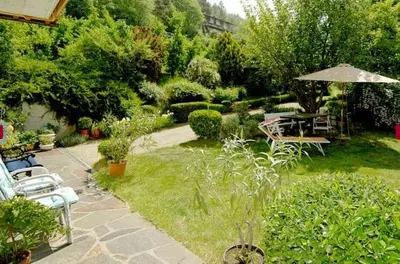 a garden with a table and chairs and an umbrella at Room Erika, Obertörgglerhof in Brixen