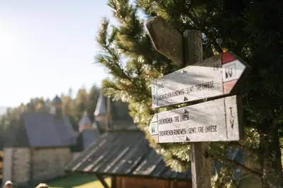 a wooden sign with distances to different cities at Berggasthof Messnerhof in Barbiano