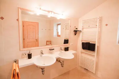 a bathroom with two sinks and a mirror at Berggasthof Messnerhof in Barbiano