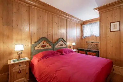 a bedroom with a red bed and wooden walls at Cozy basement flat just few steps from centre in Cortina dʼAmpezzo