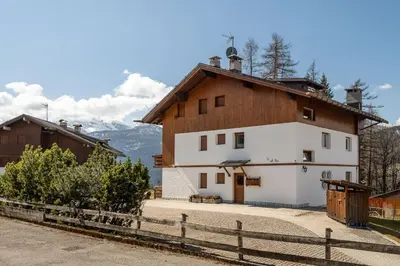 a white and brown house with a fence at Cozy basement flat just few steps from centre in Cortina dʼAmpezzo