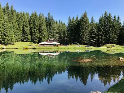 a large lake with a house in the background at Cozy basement flat just few steps from centre in Cortina dʼAmpezzo