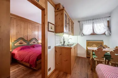 a bedroom with a bed and a sink and a table at Cozy basement flat just few steps from centre in Cortina dʼAmpezzo