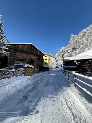 a snow covered road with a building and a barn at B&B Ciesa la Vèrda in Rocca Pietore
