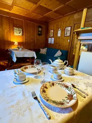 a table with plates and wine glasses on it at B&B Ciesa la Vèrda in Rocca Pietore