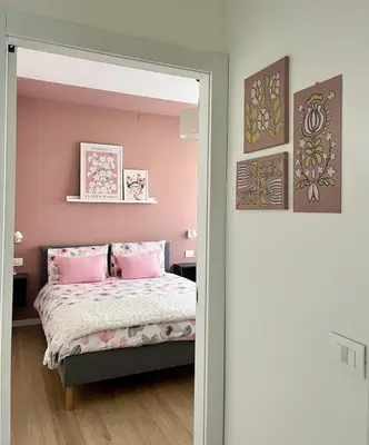a bedroom with pink walls and a bed with pink pillows at The Cozy Peak - 360 Dolomites View in Agordo