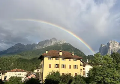 a rainbow over a building in front of a mountain at The Cozy Peak - 360 Dolomites View in Agordo