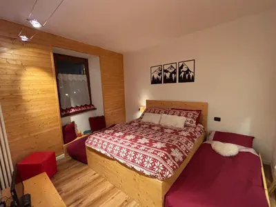 a bedroom with a bed with a red bedspread at Ciasa Cermis in Cavalese