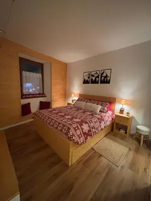 a bedroom with a bed and two tables and a window at Ciasa Cermis in Cavalese