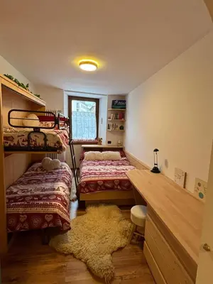 a bedroom with two beds and a desk and a rug at Ciasa Cermis in Cavalese