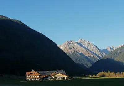 a house in the middle of a valley with mountains at Branterhof in Rasun di Sopra