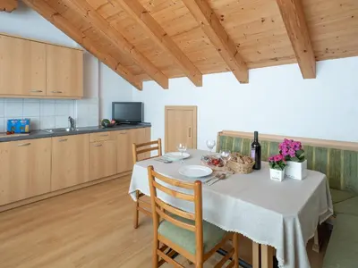 a dining room with a table with chairs and a kitchen at Branterhof in Rasun di Sopra