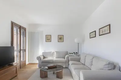 a white living room with a couch and a tv at Ciasa Remo 2 by WelcHome in San Vito di Cadore