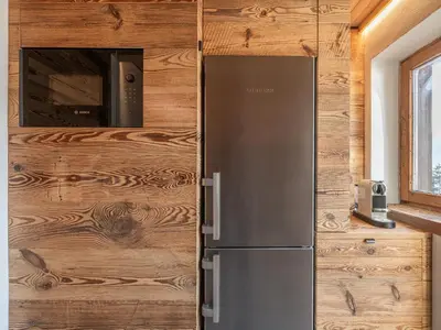 a refrigerator in a kitchen with a wooden wall at Casa Poligrafica 2, panoramica e super confortevole in Cortina dʼAmpezzo
