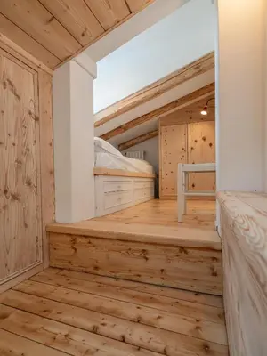 a room with wooden flooring and a bedroom with bunk beds at Casa Poligrafica 2, panoramica e super confortevole in Cortina dʼAmpezzo