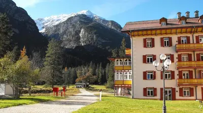 a large building with a mountain in the background at Villaggio Ploner in Dobbiaco