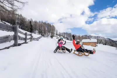 two people are riding on a snowmobile in the snow at Gasthof Greif in Sarntal