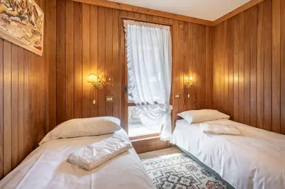two beds in a room with a window at Cozy 3 bedroom with beautiful view and access to garden in Cortina dʼAmpezzo