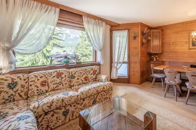 a living room with a couch and a table at Cozy 3 bedroom with beautiful view and access to garden in Cortina dʼAmpezzo