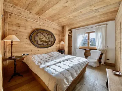 a bedroom with a large bed and a table and chairs at Luxury flat with views - few steps from centre in Cortina dʼAmpezzo