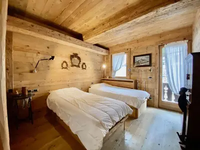 two beds in a room with wooden walls at Luxury flat with views - few steps from centre in Cortina dʼAmpezzo