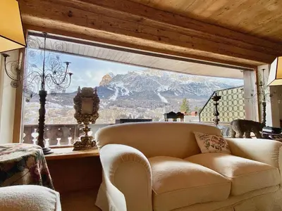 a living room with a couch and a large window at Luxury flat with views - few steps from centre in Cortina dʼAmpezzo