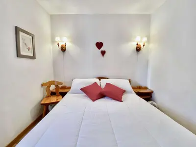 a bedroom with a white bed with two red pillows at Cozy 3 bedroom in amazing location in Cortina dʼAmpezzo