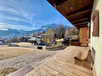 a wooden porch with a view of the mountains at Cozy 3 bedroom in amazing location in Cortina dʼAmpezzo