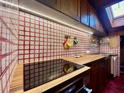 a kitchen with a sink and a red tiled wall at Cozy 3 bedroom with beautiful views in Cortina dʼAmpezzo