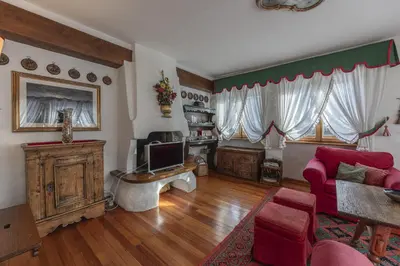 a living room with a red couch and a tv at Casa Coccola, panoramica e immersa nel verde in Cortina dʼAmpezzo