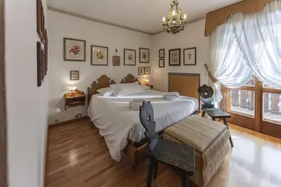 a bedroom with a large bed and a chair at Casa Coccola, panoramica e immersa nel verde in Cortina dʼAmpezzo