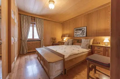 a bedroom with a large bed and a desk at Casa Merisanda, confortevole e immersa nel verde in Cortina dʼAmpezzo