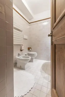 a white bathroom with a toilet and a sink at Casa Merisanda, confortevole e immersa nel verde in Cortina dʼAmpezzo