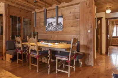 a dining room with a wooden table and chairs at Casa Merisanda, confortevole e immersa nel verde in Cortina dʼAmpezzo