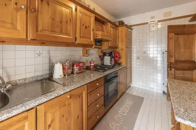 a kitchen with wooden cabinets and a stove at Casa Merisanda, confortevole e immersa nel verde in Cortina dʼAmpezzo