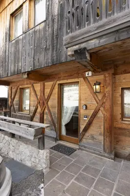 a wooden cabin with a bench and a door at Casa Col 3, graziosa e confortevole a due passi dalle piste in Cortina dʼAmpezzo